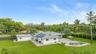 Expansive backyard featuring a paver patio, in-ground pool with a spillover spa, solar panel array, and mature landscaping