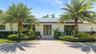 Exterior facade featuring a paved stone driveway, double-door entrance, integrated solar panels, and mature palm trees