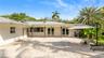 Expansive paver patio featuring a covered area with ceiling fans, dual French door entries, and mature landscaping