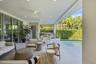 Covered outdoor patio featuring light-toned tile flooring, recessed ceiling lighting, ceiling fans, and a built-in outdoor kitchen with an integrated 