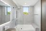 Bathroom featuring floor-to-ceiling stone-finish tile, an integrated soaking tub with a glass panel, a built-in stone ledge, and a backlit mirror