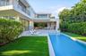 Contemporary multi-level exterior featuring stucco facade, rectangular swimming pool, concrete patio, second-story balconies with horizontal railings,