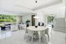Open-concept interior featuring large-format polished stone flooring, tray ceilings with recessed lighting, floor-to-ceiling windows, and a staircase 