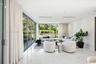 Open-concept interior featuring large-format polished stone flooring, floor-to-ceiling glass sliding doors, expansive glass windows, and recessed ligh
