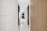 Hallway featuring large-format light-toned stone flooring, recessed ceiling lighting, and solid wood-finish doors with brushed-metal hardware