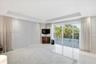 Tray ceiling with recessed lighting, large format tile flooring, and sliding glass doors opening to a balcony with metal railing