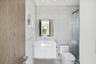 Modern bathroom featuring a white floating vanity with a vessel sink, integrated LED-lit mirror, glass-enclosed shower, and stone-finish floor tiling