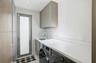 Utility room featuring custom cabinetry, a solid surface countertop, an undermount sink with a high-arch faucet, and a glass-panel door
