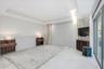 Tray ceiling with recessed lighting, integrated wood-slat wall paneling, built-in wooden shelving, oversized tile flooring, and floor-to-ceiling slidi