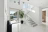Grand entryway featuring high ceilings, large-format tile flooring, a glass-railed staircase, and a floor-to-ceiling glass-paneled front door