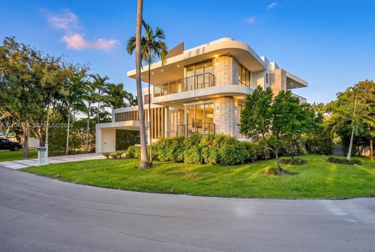 Modern multi-level exterior featuring curved architectural lines, stone-accented facade, expansive glass sliding doors, integrated balcony railings, a