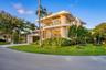 Modern multi-level exterior featuring curved architectural lines, stone-accented facade, expansive glass sliding doors, integrated balcony railings, a