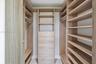 Custom walk-in closet featuring wood-finish cabinetry, built-in shelving, integrated dresser drawers, and metal hanging rods