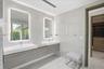 Floating double vanity with wood-finish cabinetry, integrated rectangular sinks, polished chrome fixtures, back-lit vanity mirrors, and floor-to-ceili
