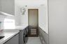 Laundry room featuring grey flat-panel cabinetry, white solid-surface countertops, integrated sink, and wood-finish door with louvered panel