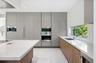 Modern kitchen featuring floor-to-ceiling flat-panel cabinetry, a large central island with white quartz countertops, integrated stainless steel appli