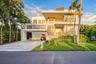 Modern multi-level exterior featuring clean geometric lines, stacked stone facade accents, multiple covered balconies with cable railings, and a wide 