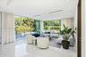 Floor-to-ceiling glass walls, polished stone flooring, recessed ceiling lighting, and metal-railed balcony overlooking an outdoor pool area