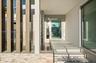 Contemporary entryway featuring vertical architectural screening, tiered stone masonry, recessed ceiling lighting, a water feature, and a glass-panele