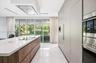 Contemporary kitchen featuring a large island with wood-finish cabinetry, a waterfall-edge stone countertop, integrated flush-panel cabinetry, stainle