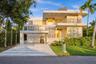 Modern multi-level exterior featuring smooth white stucco, stacked stone accents, two expansive balconies with metal railings, and a covered carport