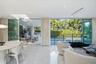 Open-concept interior featuring large-format stone flooring, floor-to-ceiling glass sliding doors, recessed lighting, and a covered outdoor patio
