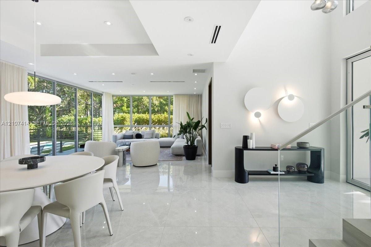 Open-concept interior featuring floor-to-ceiling glass walls, large-format tile flooring, recessed lighting, and sculptural wall-mounted fixtures