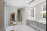 Dual floating vanity with horizontal wood-finish cabinetry, integrated rectangular sinks, and backlit mirrors, accented by large-format neutral wall t