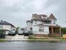 Multi-story exterior featuring a conical turret, wraparound covered porch, shingle-style roofline, and paved driveway
