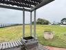 Outdoor pergola featuring wooden lattice and slats, stone planter, and metal perimeter railing