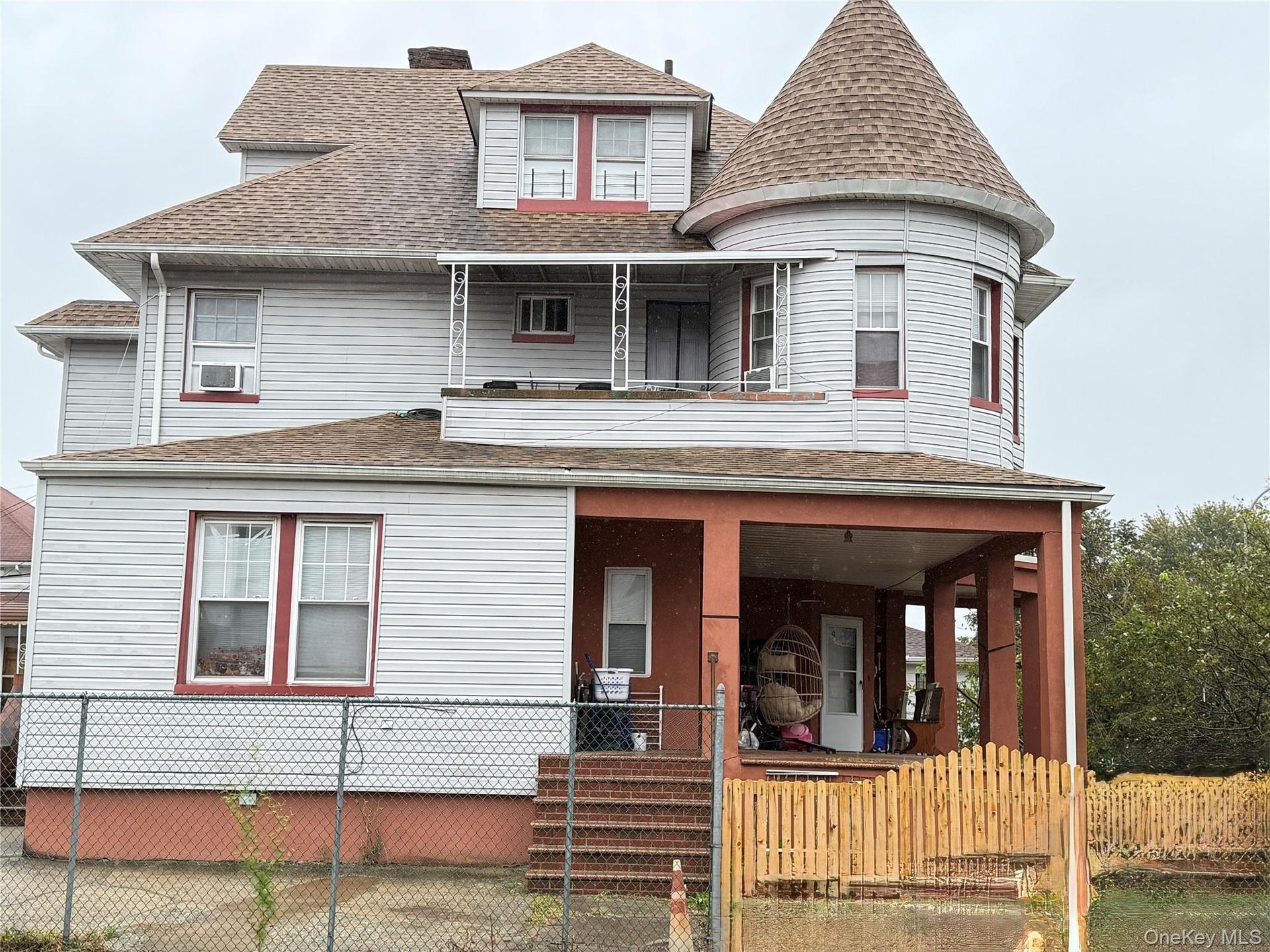 Victorian-style exterior featuring a prominent corner turret, covered front porch, second-story balcony, horizontal siding, and a shingled roof