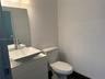 White vanity with a rectangular vessel sink and a single-handle chrome faucet, paired with a frameless wall mirror, overhead lighting fixture, and a s