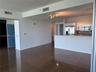 Open concept living area featuring large-format tile flooring, a kitchen breakfast bar with brick-style siding, stainless steel appliances, and multi-