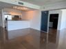 Kitchen featuring white cabinetry, stainless steel appliances, a breakfast bar with textured stone-style cladding, large-format tile flooring, and a s