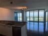 Open-concept kitchen featuring stone countertops, an integrated dual-basin sink, and a stainless steel dishwasher