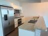 Kitchen featuring white cabinetry, stone-finish countertops, stainless steel appliances, a double-basin sink with a pull-down faucet, and a tiled back