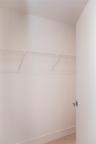Storage space featuring a white wire shelving system, a mounted garment rod, and neutral flooring