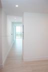 Hallway featuring light-toned flooring, recessed ceiling lighting, and floor-to-ceiling glass paneling