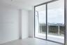 Floor-to-ceiling glass sliding doors, wood-finish flooring, and a private balcony featuring a glass railing and urban skyline scenery