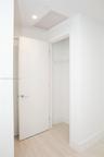 Solid core interior door featuring a satin chrome lever handle, wood-finish flooring, and a built-in closet with integrated shelving