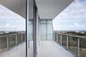 Covered balcony featuring expansive glass panel railings, floor-to-ceiling sliding glass doors, and tiled flooring