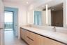 Floating vanity with wood-finish cabinetry, dual undermount sinks, light-toned stone countertop, integrated vertical LED mirror lighting, and polished