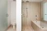 Bathroom featuring stone-finish wall and floor tiling, glass-enclosed shower with rainfall and handheld showerheads, deep soaking tub, and enclosed to