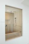 Walk-in shower enclosure featuring floor-to-ceiling neutral stone-finish tile, rainfall showerhead, handheld shower attachment, integrated wall niche,
