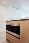 Kitchen island featuring wood-finish cabinetry, integrated stainless steel microwave drawer, and stone countertop with waterfall edge