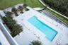 Rectangular swimming pool with stepped entry, surrounded by a paved deck featuring shaded cabanas, palm landscaping, and perimeter metal railings