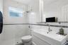 Bathroom featuring white wall tile with a mosaic accent border, a glass-enclosed shower, a floating vanity with an integrated sink, and brushed-nickel