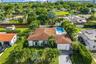 Single-story residence featuring a hipped roof, attached garage, bay window, and a rear swimming pool set within a manicured landscape