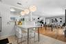 Kitchen peninsula with a solid-surface countertop and integrated breakfast bar, complemented by three spherical pendant light fixtures, large-format t