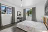 Bedroom featuring wood-finish flooring, dual windows, and a multi-pendant light fixture